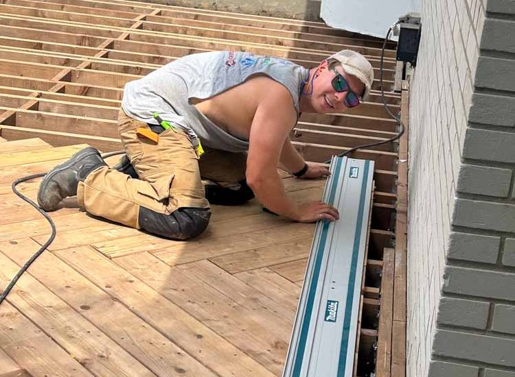 Overview of a deck construction site showing the wooden framework and partially installed wooden planks, capturing the progress in an outdoor building project.